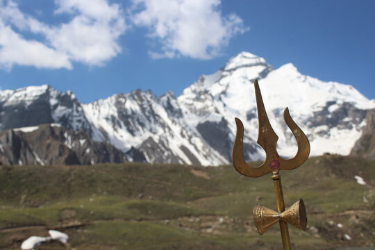 a golden colored trident in front of adi kailash mountain 