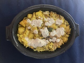 Vegetable breyani with white sauce in a bowl on a dark blue tablecloth