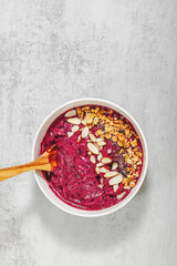 Bright and creamy berry smoothie bowl topped with granola and almonds