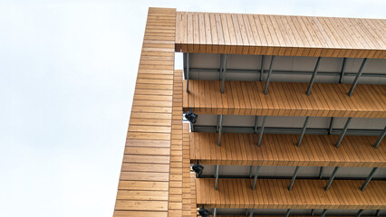 Modern wooden architectural design of outdoor stage with stacked beams and open spaces against a cloudy blue sky. Concept of contemporary architecture