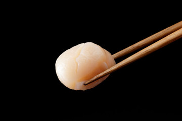 箸で持ち上げた帆立の貝柱の刺身