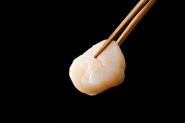 箸で持ち上げた帆立の貝柱の刺身