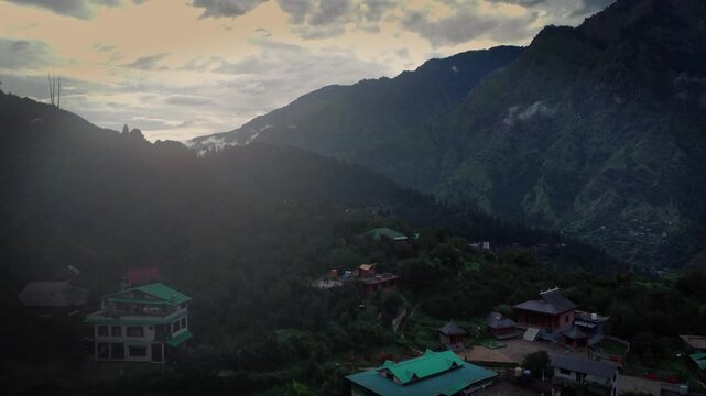 Beautiful drone shot of a village in Parvati valley with old rustic houses at the foothills of Himalayas in Himachal Pradesh, India