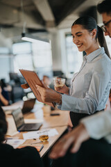 Multiracial business associates are discussing a project together in a modern office setting. They are analyzing documents and enjoying a collaborative work environment.