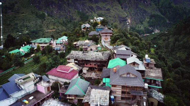 Beautiful drone shot of a village in Parvati valley with old rustic houses at the foothills of Himalayas in Himachal Pradesh, India