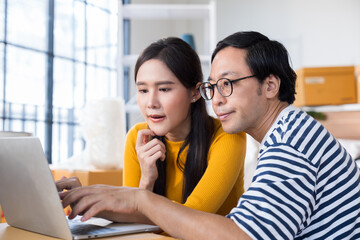 Happy young Asian couple with laptop at home.