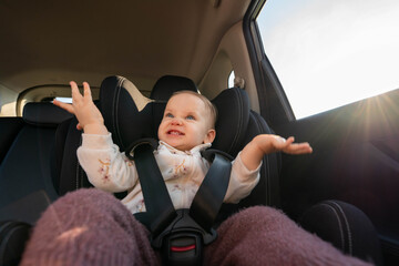 A cheerful baby in a car seat, clapping hands with excitement during a family road trip. Concept of...