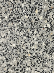 Polished terrazzo surface with a mix of black, white, and gray stone fragments, creating a seamless and modern texture.