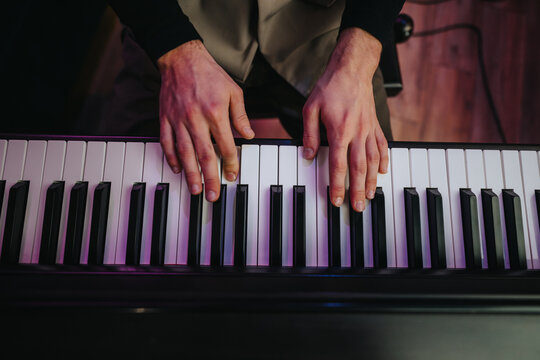 A detailed view of a musician's hands playing the piano, focusing on finger placement and movement. The image conveys creativity, music passion, and the intricacies of piano performance.
