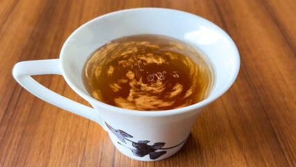 木目のテーブルに置かれた紅茶　かき混ぜた後の水面の流れ