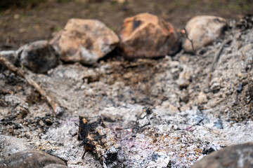 Ashes and charred wood inside a rock lined fire pit