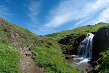 Obraz premium Majestic waterfall lush green hills panoramic landscape vibrant blue sky