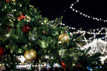 Christmas tree decorated with colorful balls and glowing lights at night