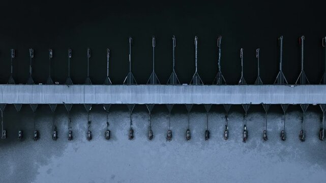Aerial footage, camera moving from left to right over empty boat dock jetty covered in snow in frozen sea lake