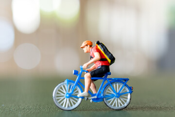Close-up shot of a figurine of a cyclist riding a blue bicycle with a backpack, Perfect for themes...