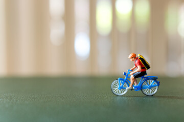 Close-up shot of a figurine of a cyclist riding a blue bicycle with a backpack, Perfect for themes of travel, adventure