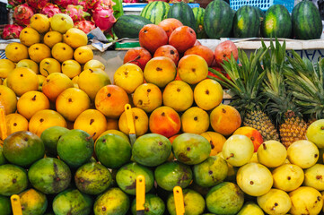 A colorful fruit display case made of mangoes and pineapples on display at the local market