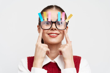 Young woman with colorful clips on glasses, smiling cheerful expression against a light background...