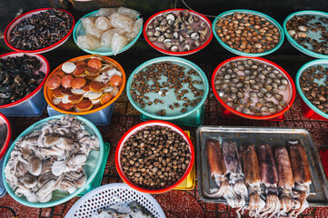 A variety of fresh edible oysters, clams, scallops, squid and fish at the local market