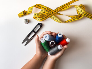 Hands holding colorful threads with scissors and measuring tape for sewing crafts