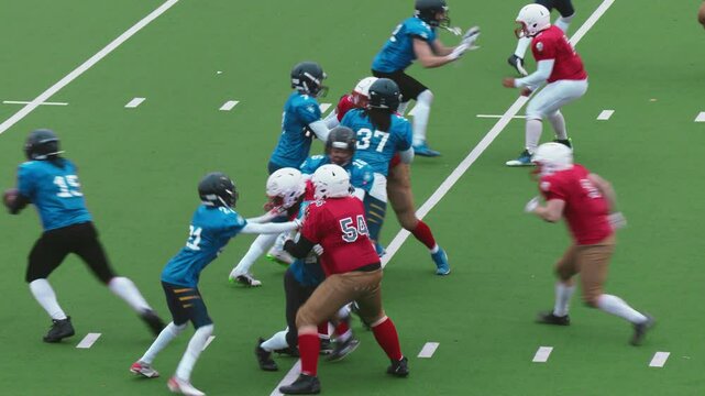 American Football Game Broadcast with Diverse Male Athletes in Red and Blue Jerseys Playing on a Green Field. Footballer Getting the Ball, Jumping Over a Competitor and Running to Make a Touchdown