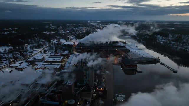 Aerial view of smoke plumes rising from industrial paper mill complex at twilight