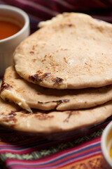 Pupusas with curtido and sauce served on a tamale leaf atop a wooden surface, highlighting traditional Central American flavors.