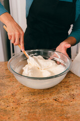 Baker in kitchen mixing vanilla frosting in bowl