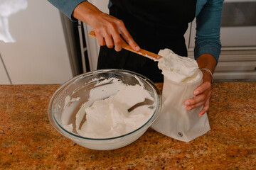 Baker adding vanilla frosting to pastry bag