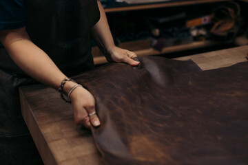Artisan handling rich brown leather sheet for tailoring crafts