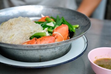 Steamed mud crab with glass noodles, green onions and chives served with nam jim jaew (seafood dipping sauce) at a street food cart in Khlong San - Bangkok, Thailand