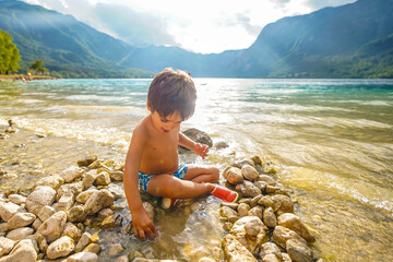 Child playing on the rocky shore of lake bohinj, slovenia