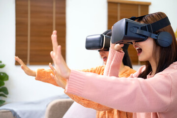 Friends playing video games wearing virtual reality glasses. Two girls having fun with vr glasses virtual reality inovation at home