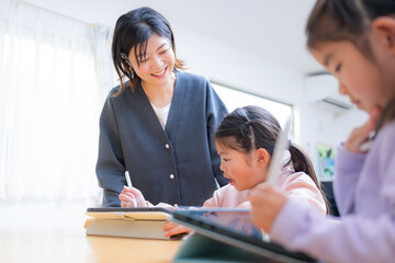 家や自宅のリビングなどで勉強や宿題をみるお母さんや先生　小学生低学年の子供