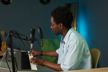 African American man playing piano and singing song in microphone