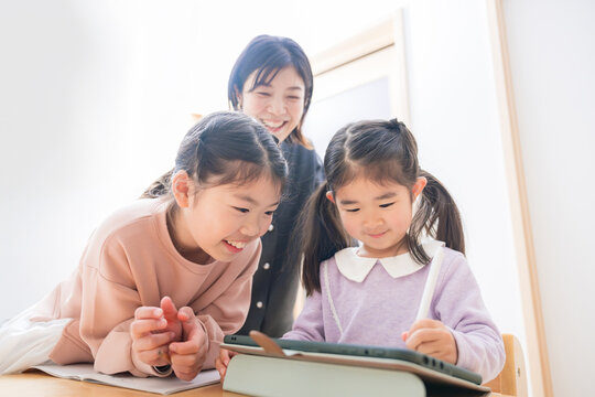 Also in the main visual! Mothers and cram school teachers looking at study and homework in the backlight. Smiling child in early elementary school: “Studying is fun even with a tablet.”