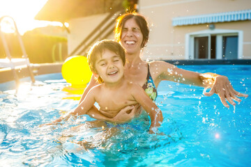 Mother and son laughing and having fun in swimming pool during summer vacation