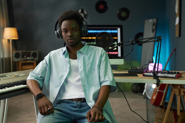 Portrait of African American young musician in headphones working in recording studio
