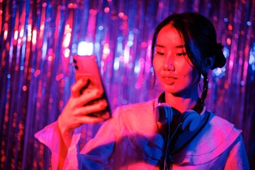 DJ with teal headphones and a bright smile holds a smartphone in front of a sparkling pink and blue streamer backdrop, creating a vibrant and lively atmosphere.