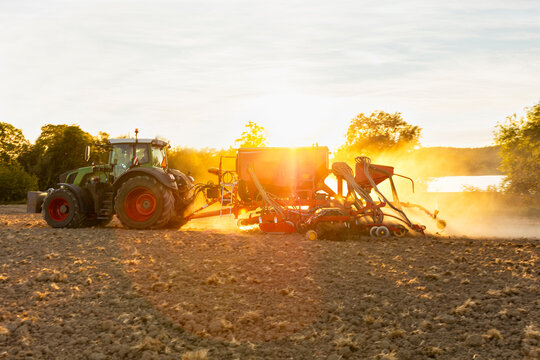 Tractor plowing field with seedbed cultivator at sunny day
