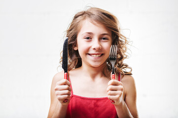 Cheerful girl holding fork and knife
