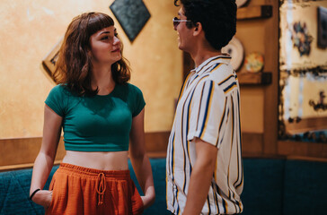 A young woman and man engage in a friendly conversation in a cozy cafe with warm lighting and...