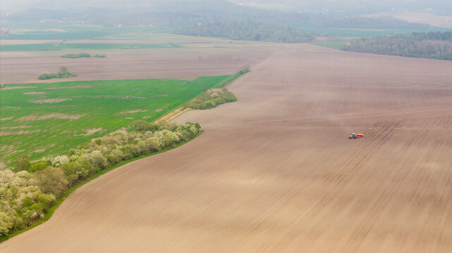 Drone point of view of tractor on agricultural field at foggy day