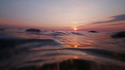 Obraz premium Sunset over calm ocean waters captured from a low perspective on the shore