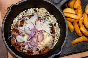 Onion Burger. Meat burger of ground meat fried in oil on a frying pan with three types of onions, close up