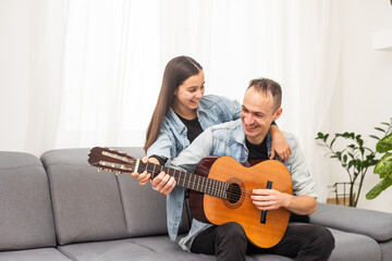 smiling father showing daughter how to play barre chord