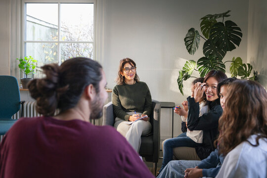 Happy family talking in front of female psychologist in office