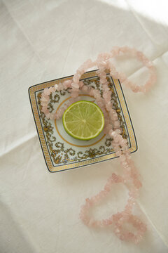Directly above shot of necklace with slice of lemon in plate on table