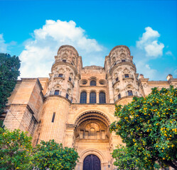 Naklejka premium Side entrance of the Malaga Cathedral (la manquita) behind a lovely garden with ornamental butter orange trees, Malaga, Andalusia (Andalucía), Spain