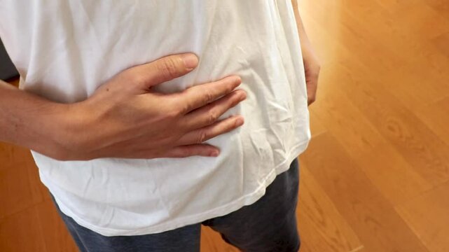 手でお腹を軽く叩く男性